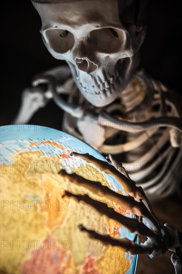 Skeleton with bony hand on globe