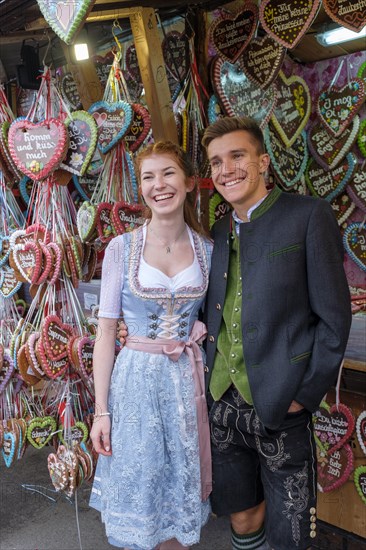 Young couple in traditional traditional traditional traditional traditional traditional traditional traditional traditional traditional costume in front of gingerbread hearts