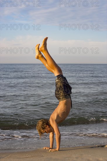 Youth doing a handstand at the Baltic Sea beach