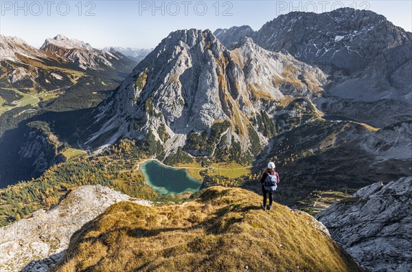 Young woman with climbing helmet looking at Seebensee from the Ehrwalder Sonnenspitze