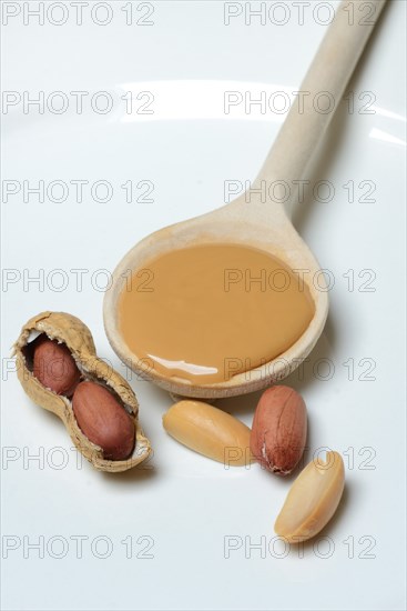 Peanut puree in cooking spoon and peanuts