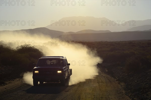 All-terrain vehicle with dust cloud on track through volcanic lunar landscape