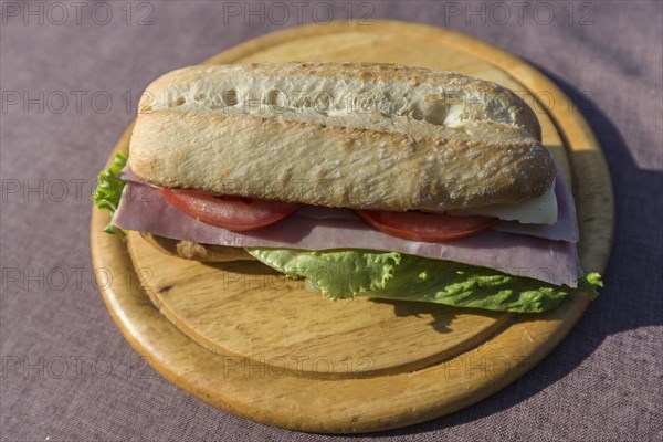 Ham and cheese baguette on a wooden plate