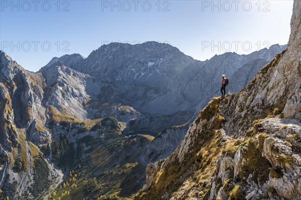 Mountaineer with climbing helmet stands on a rocky outcrop