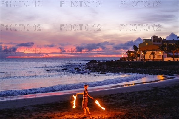 Woman with torches dancing on the beach of La Playa at dusk