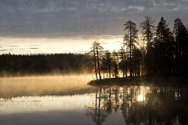 Sunrise with fog at a lake in the Finnish Taiga