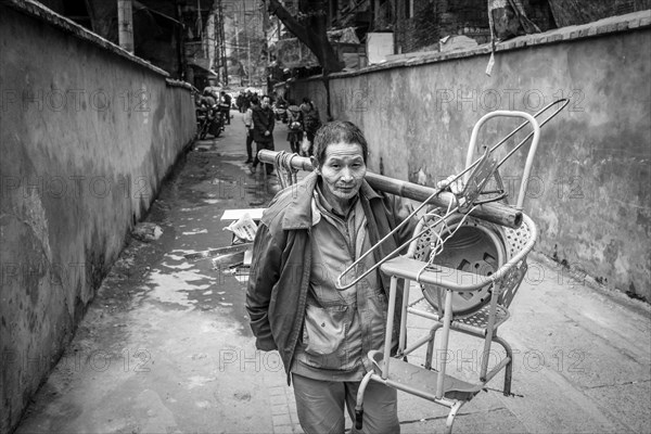 Street scene in an old town quarter of Chongqing. A woman with her furniture moves out of her apartment