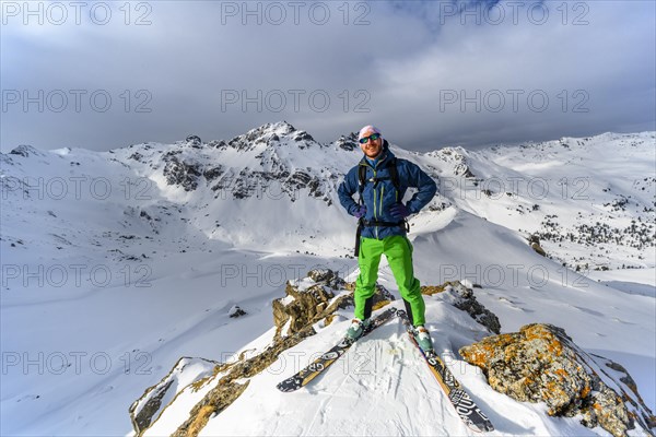 Ski tourers in front of a snow-covered mountain landscape