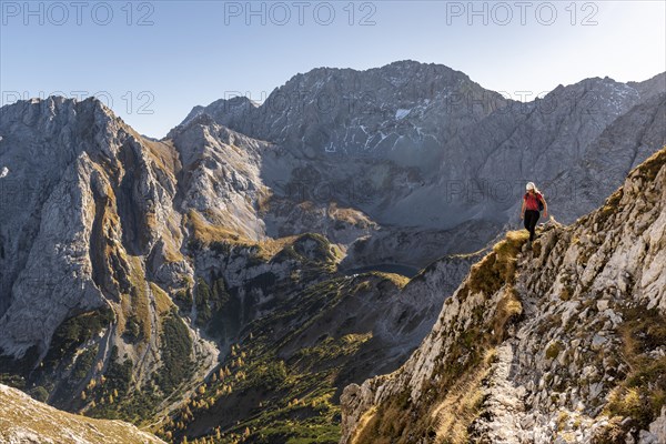 Mountaineer with climbing helmet running on a steep mountain slope