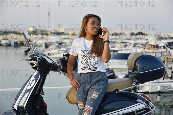 Woman with Vespa 125 Primavera in the port of Penelope