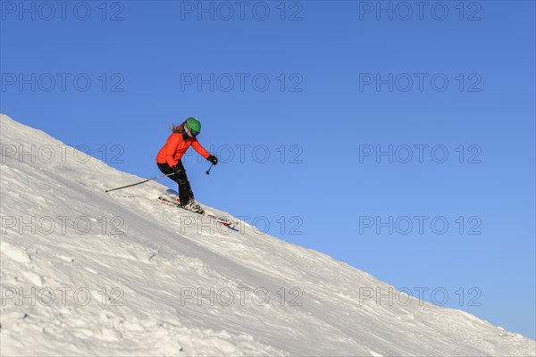 Female skier descending steep slope