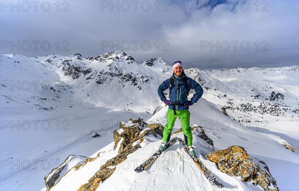 Ski tourers in front of a snow-covered mountain landscape