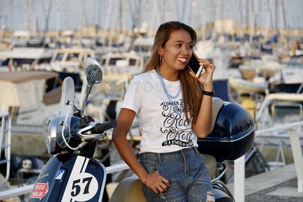 Woman with Vespa 125 Primavera in the port of Penelope