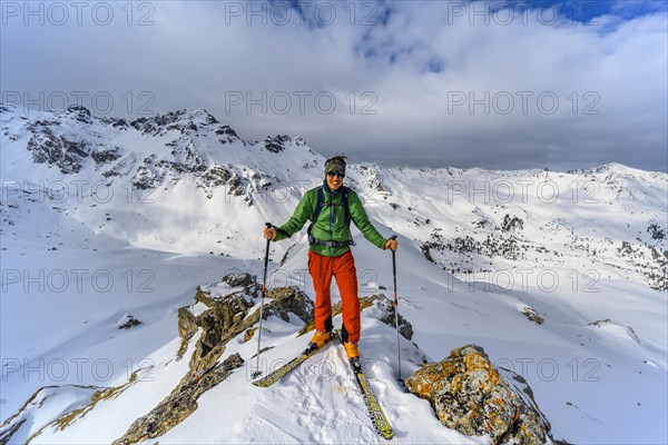 Ski tourers in front of a snow-covered mountain landscape