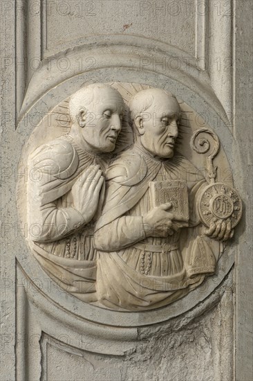 Relief of two priests at the entrance of a church