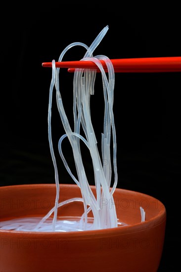 Asian glass noodles on chopsticks over bowl