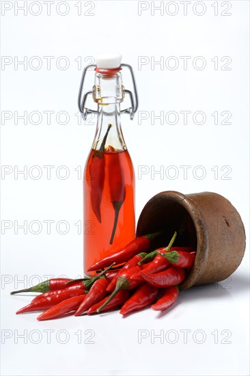 Chili oil in bottle and red chillies in ceramic vessel