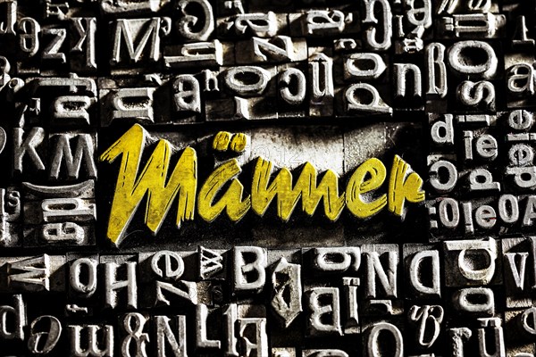 Old lead letters with golden writing show the word Maenner