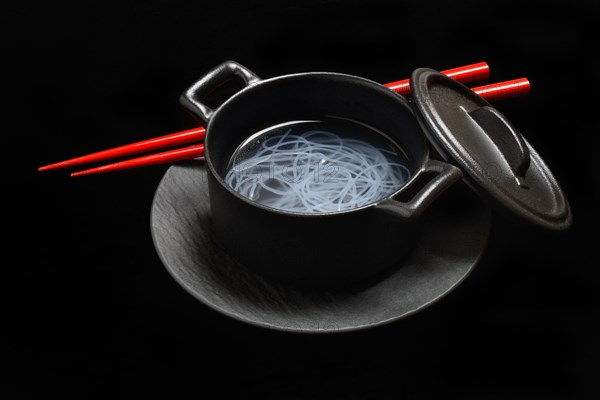 Asian glass noodles in pot and red chopsticks