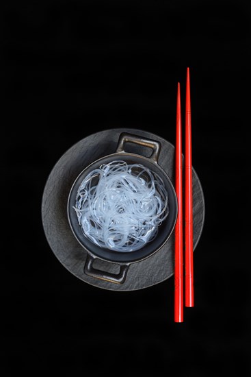 Asian glass noodles in pot and red chopsticks