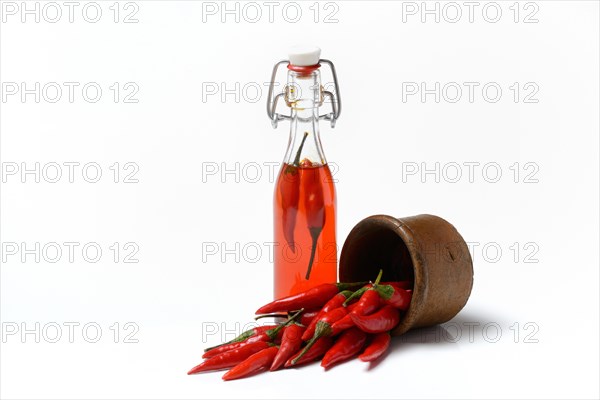 Chili oil in bottle and red chillies in ceramic vessel