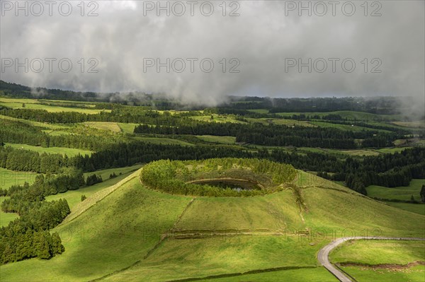 Green overgrown volcanic crater is filled with water