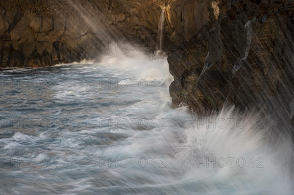 Surf on a steep coast with a small waterfall