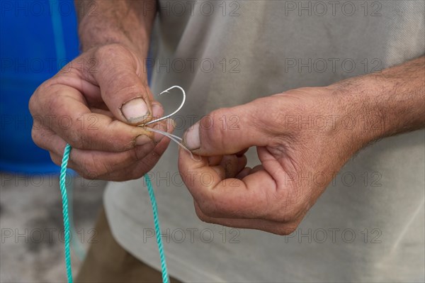 Fisherman knots a fishing hook on the line