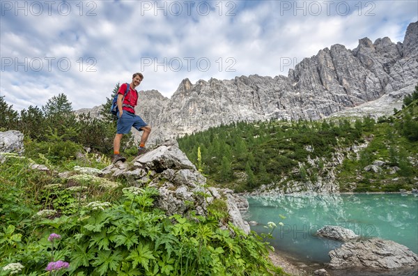 Hiker stands on a rock at turquoise green Sorapis lake