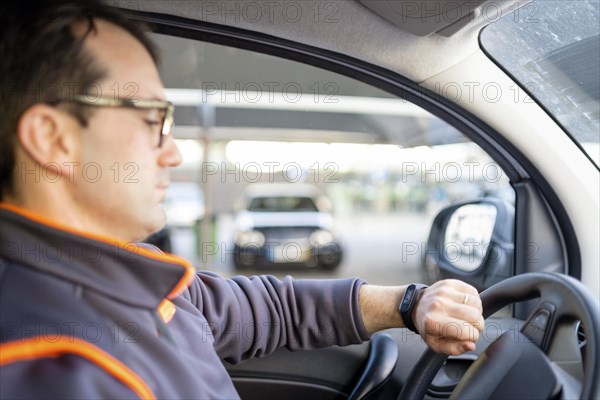 Delivery man driving a car and looking on the watch