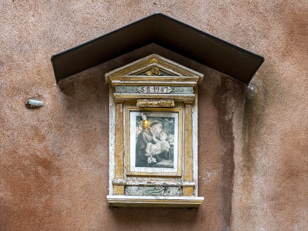 Small wayside shrine with St. Anthony on a house wall