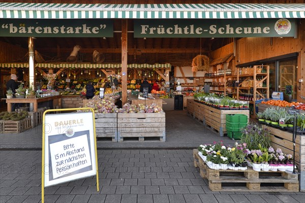 Market stall with regional food from a farmer with a warning about coronavirus