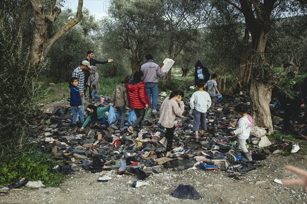 Refugees look for shoes from a pile of donations