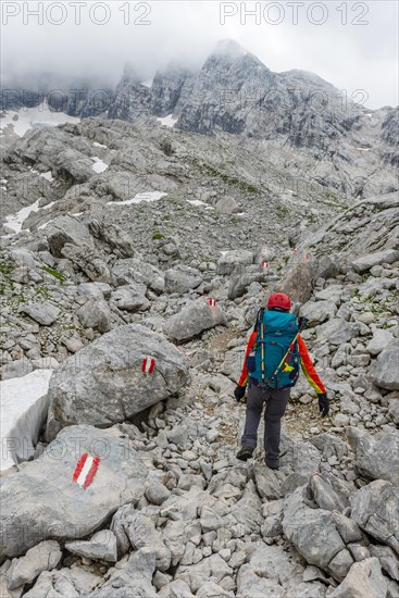 Mountaineer runs through rocky alpine terrain on a marked route