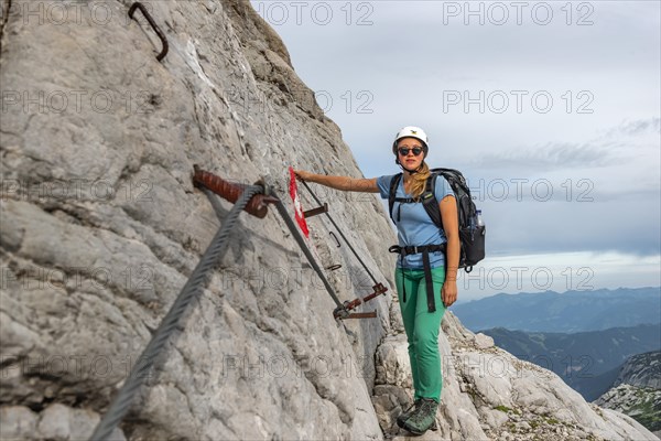 Mountaineer on secured route on steep rock face