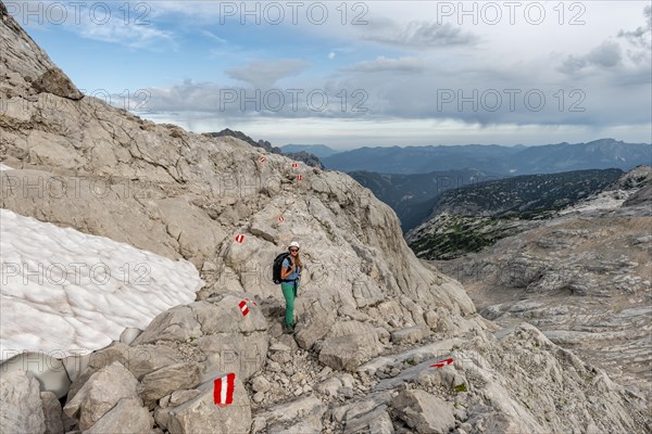 Mountaineer on marked route through rocky alpine terrain