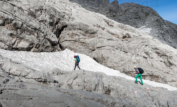Female mountaineers on marked route through rocky alpine terrain