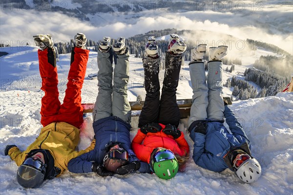 Skiers lie in the snow and stretch their legs in the air