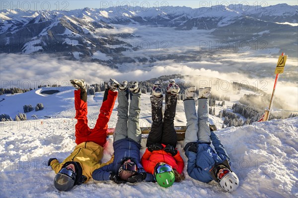 Skiers lie in the snow and stretch their legs in the air