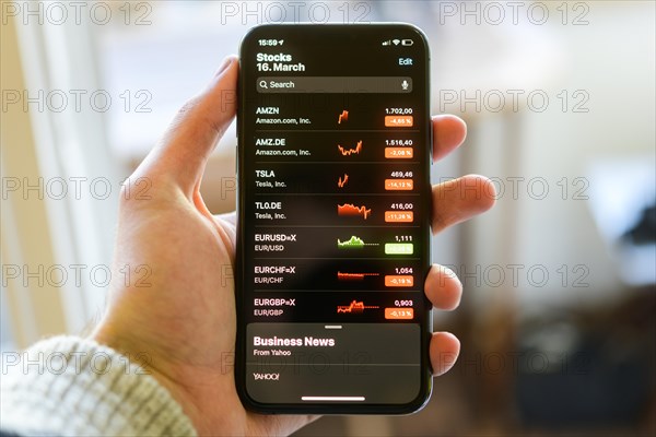 Hand holds iPhone 11 with stock app on display