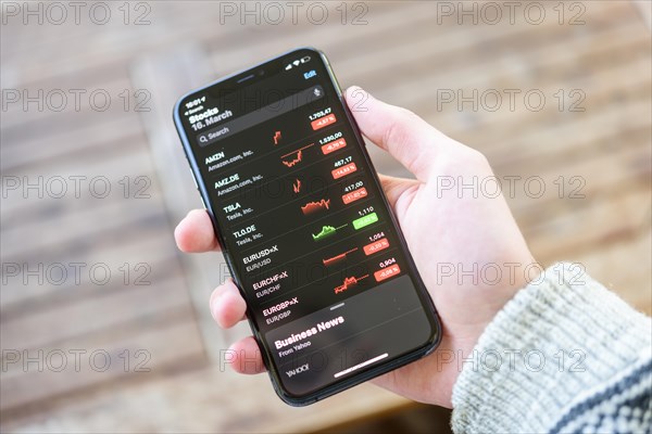 Hand holds iPhone 11 with stock app on display