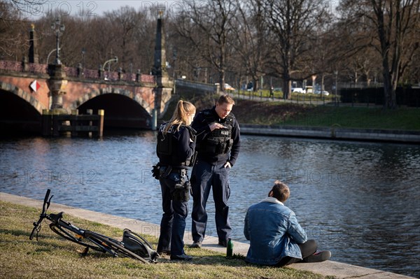 Policemen admonish passers-by on the banks of the Spree