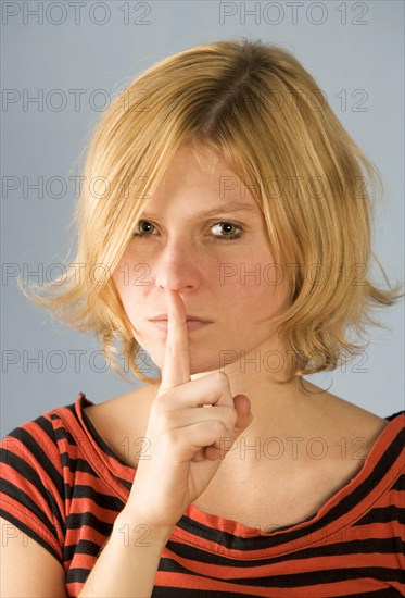 Teenager holds index finger to mouth