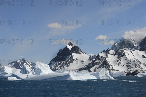 Floating icebergs off mountain peaks with snow