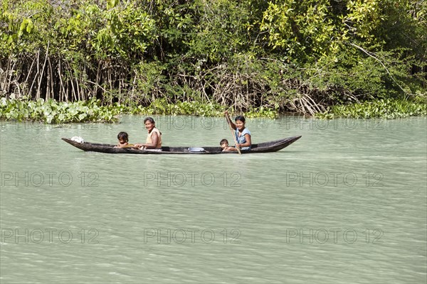 Native woman with small children rowing in a dugout boat in the Orinoco Delta