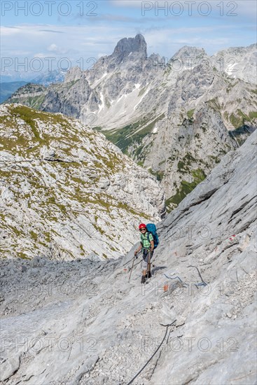 Hiker on a rocky route secured with a wire rope from Simonyhuette to Adamekhuette