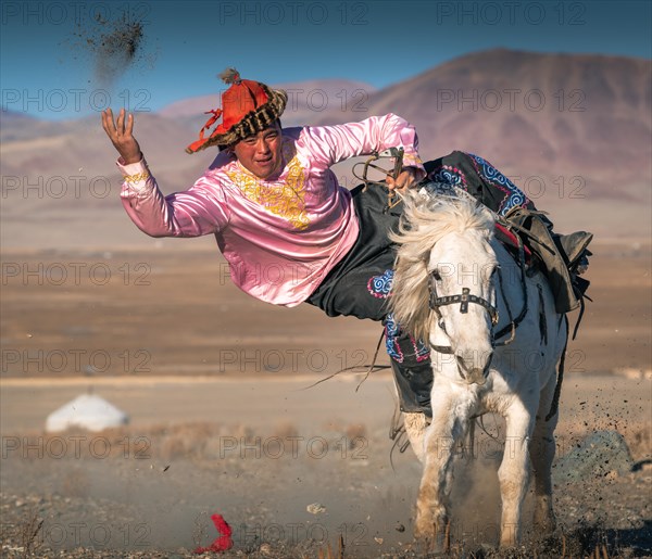 Kazakh rider picking up the coin from the ground