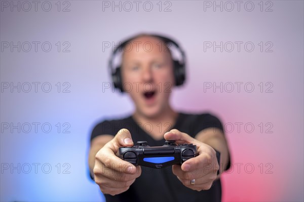 Gamer with headphones and gamepad having a lot of fun