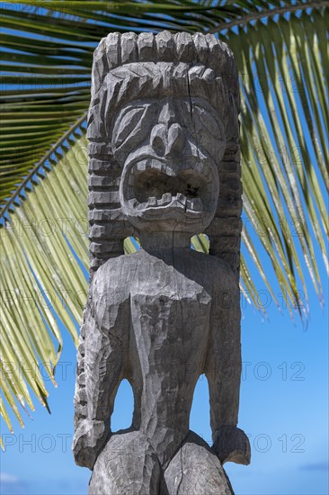 Guardian figure Tiki in front of palm leaf