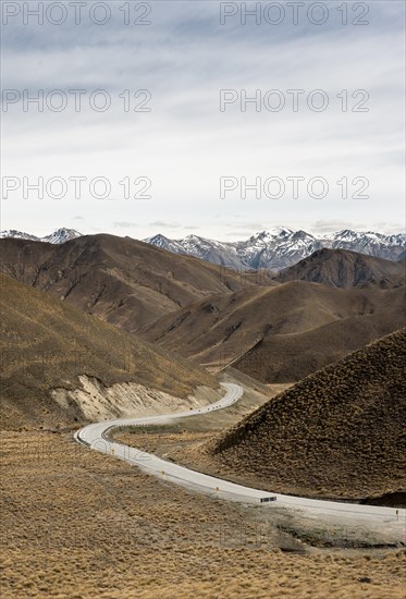 Barren mountain landscape with pass road, snow-covered mountain peaks in the back